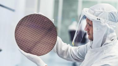 Scientist in white suit holding chip